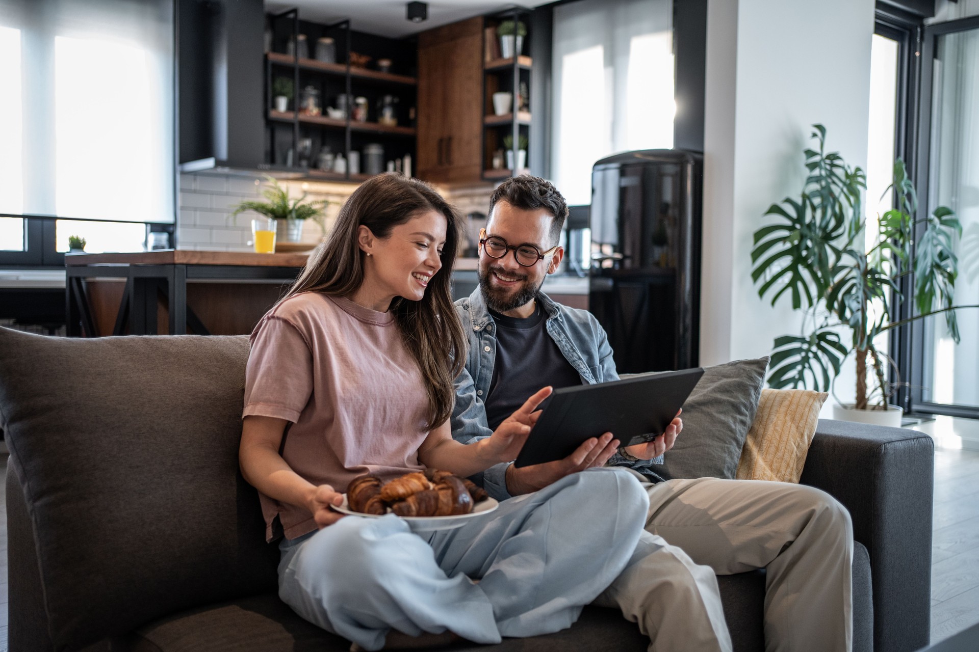 Young couple enjoying breakfast and technology at home